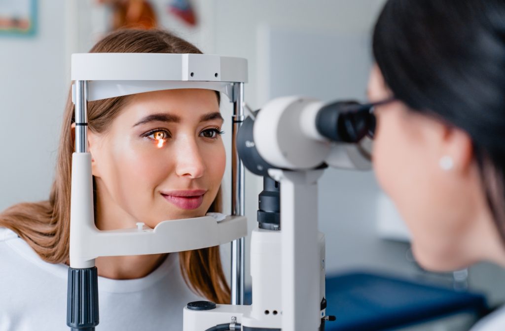 An optometrist examines a female patient with a slit lamp.