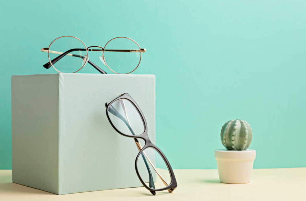 Two pairs of glasses on a box with green background.