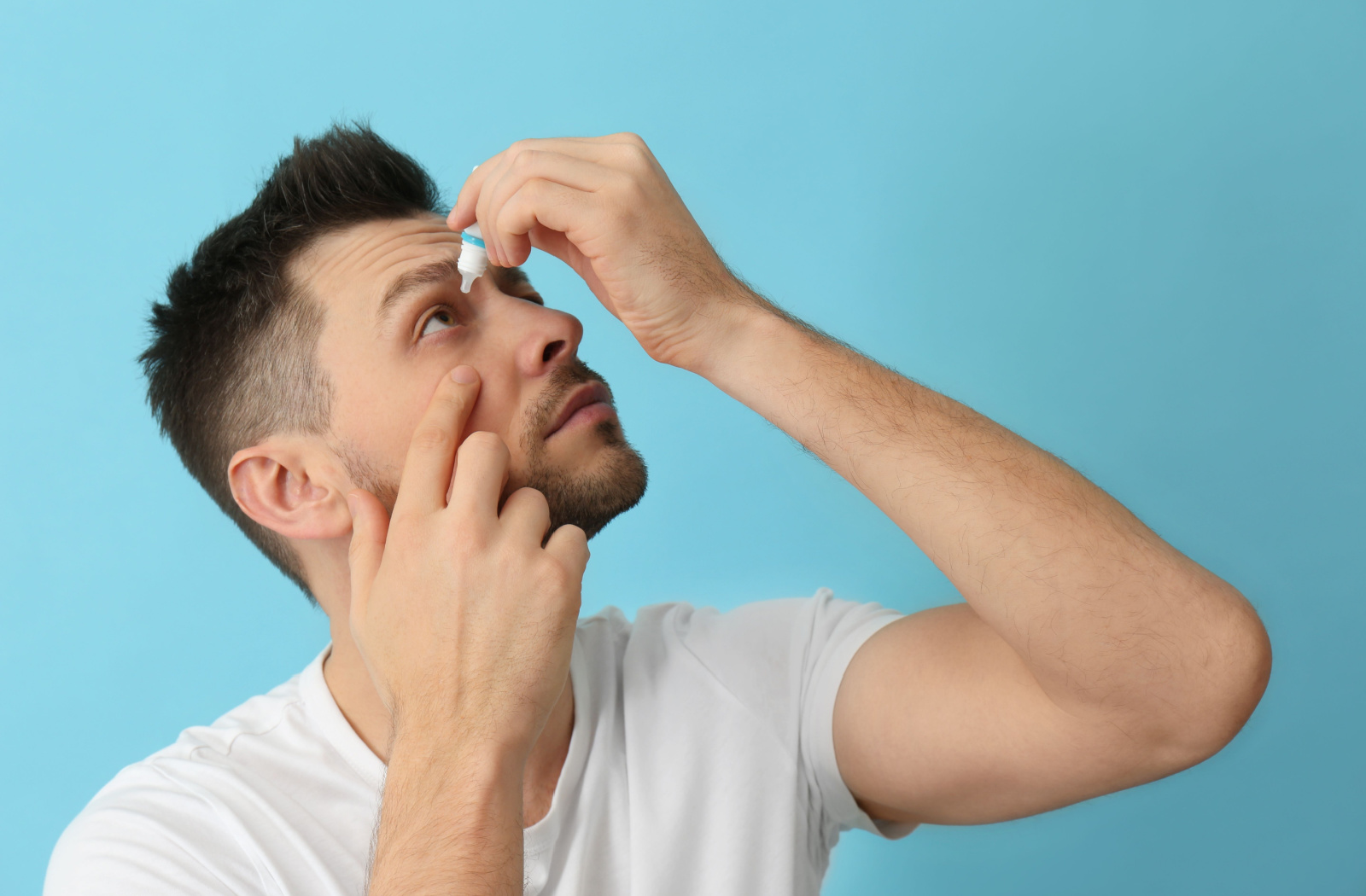 A man inserting eye drops to help manage his glaucoma.