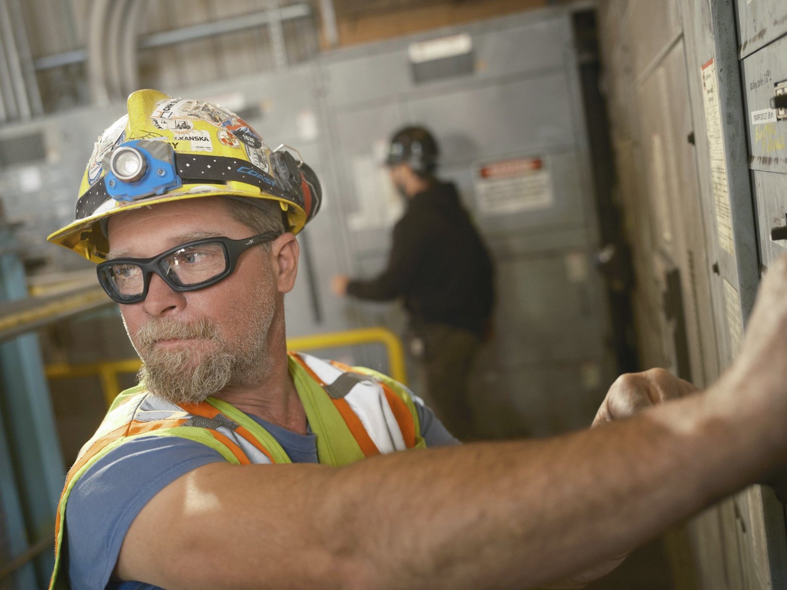 A man wearing a hard hat and prescription safety glasses.