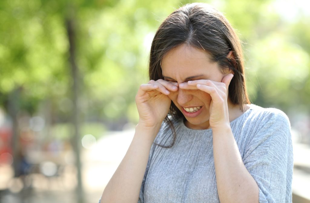 A person rubbing both of their eyes with their hands as their contact lenses are irritating their eyes.